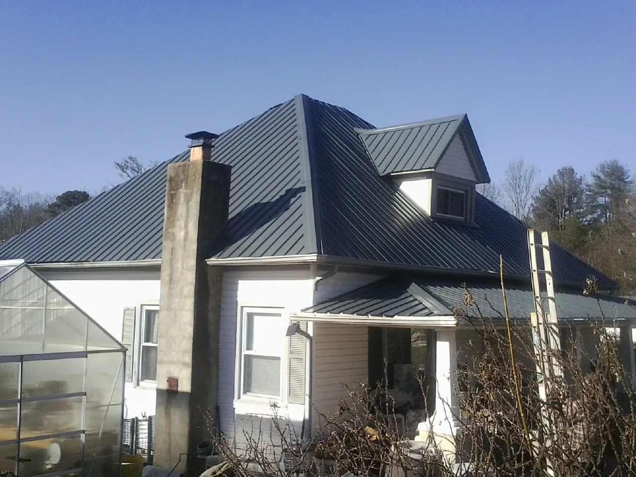 Dark blue standing seam metal roof on a white farmhouse with dormer — Slate & Tile Roof Repair by Roofing Brothers in El Dorado