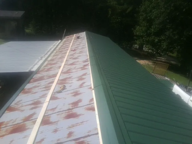 Old rusted panels beside newly installed green metal roofing — Wind Damage Roof Repair by Roofing Brothers in El Dorado