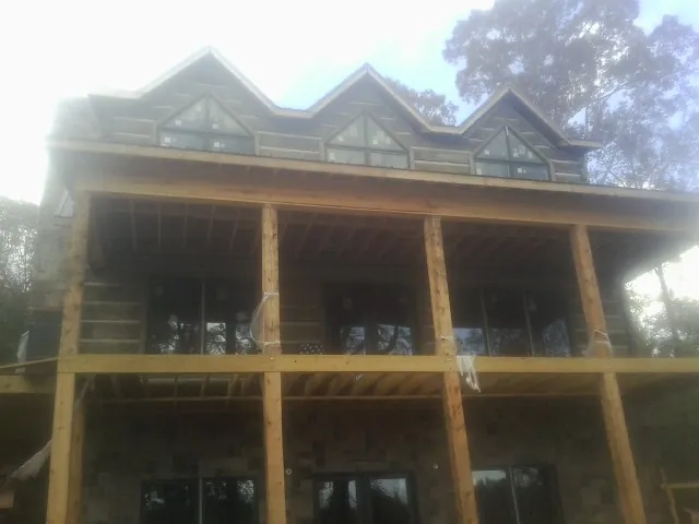 Dormers and porch framing on a large log home under construction — Roof Coating work by our crew in El Dorado
