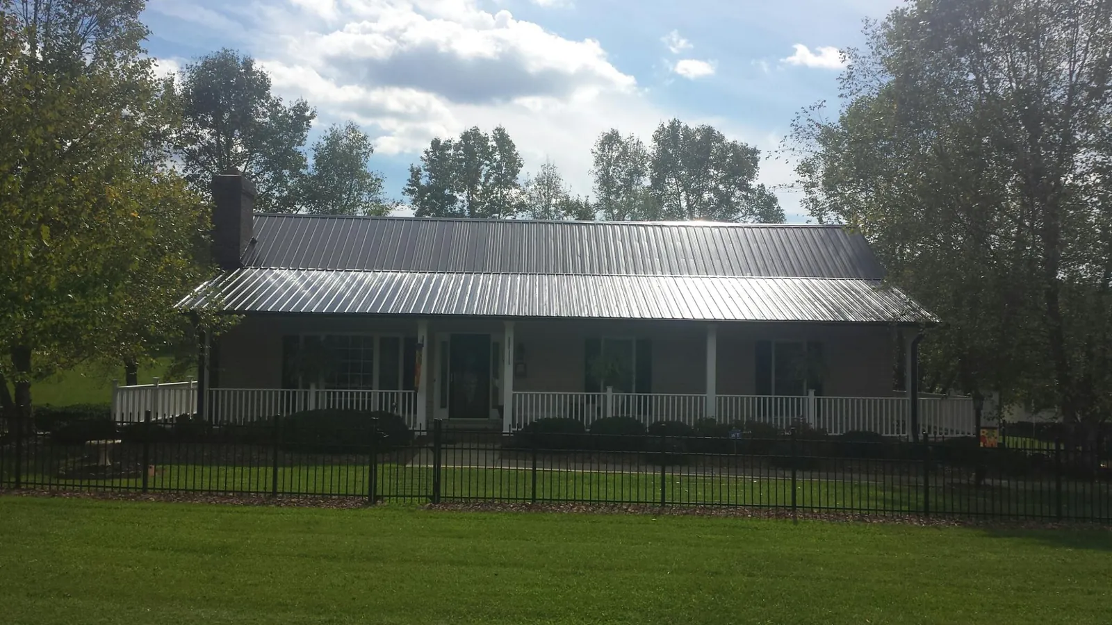 Gray metal roof on a brick ranch with a full width front porch — Gutter Guard Installation work by our crew in El Dorado